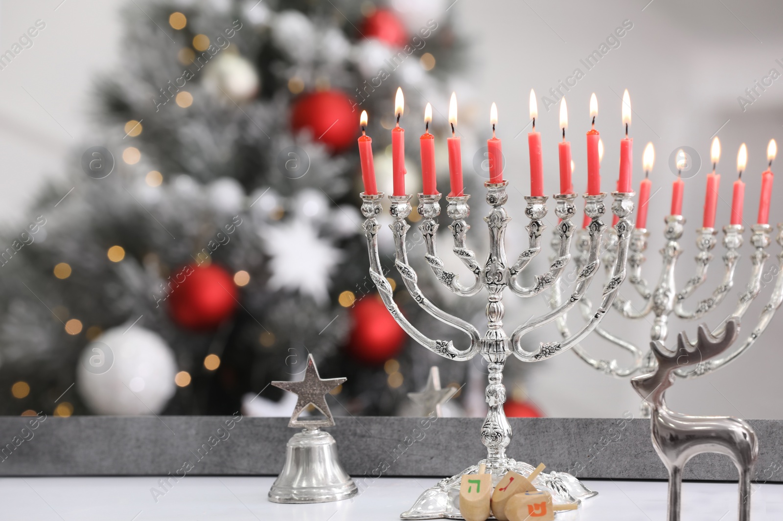 Photo of SIlver menorah, Christmas decorations and dreidels with symbols He, Pe, Nun, Gimel near mirror on table, space for text. Hanukkah symbol