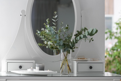 Photo of Beautiful eucalyptus branches on dressing table in room. Interior design