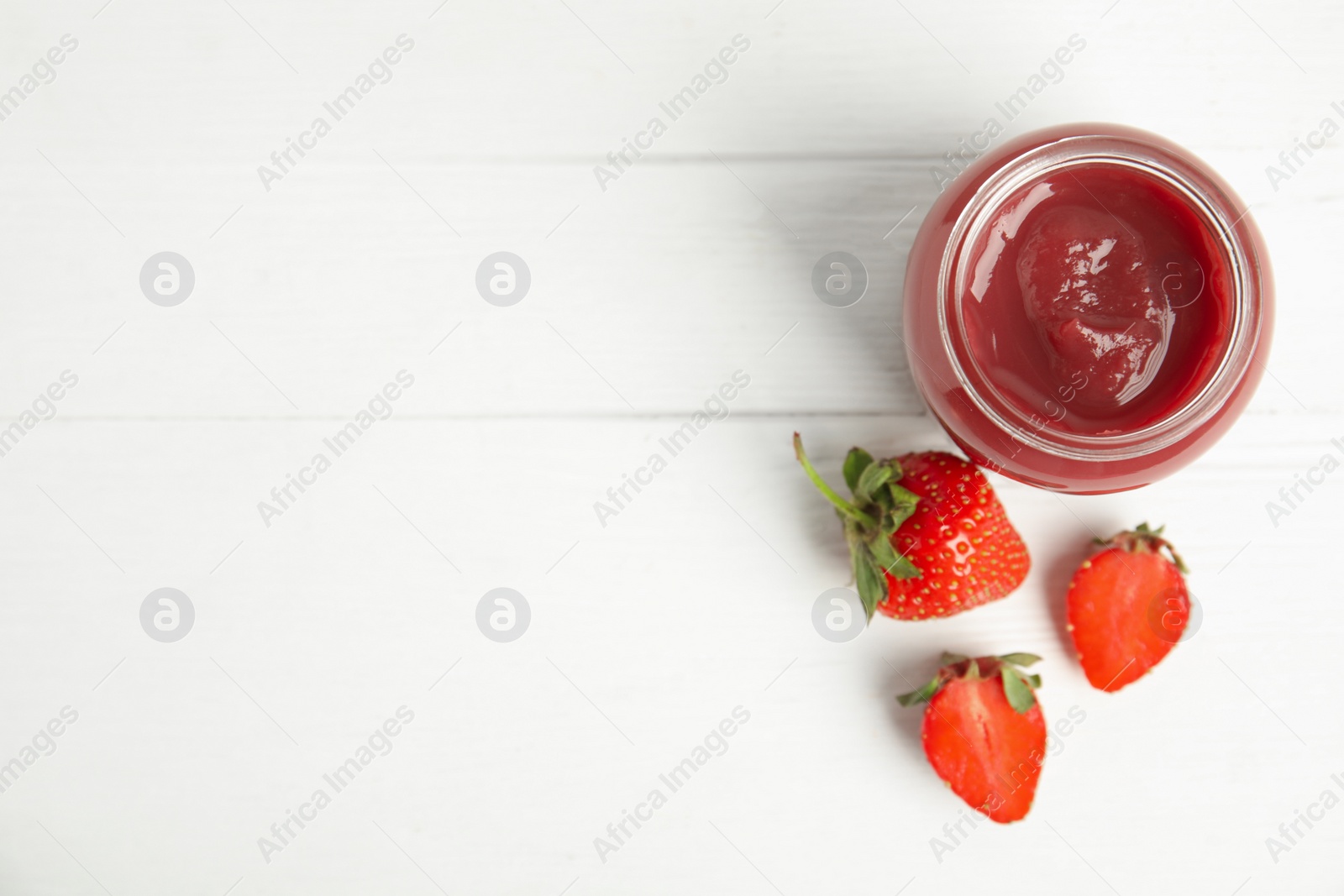 Photo of Healthy baby food in jar and fresh strawberries on white wooden table, flat lay. Space for text