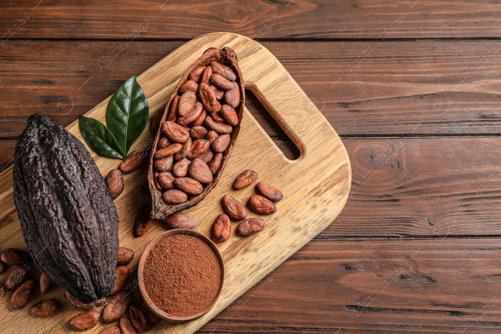 Photo of Board with cocoa pods, beans and powder on wooden table, top view with space for text