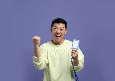 Emotional asian man with vip pass badge on purple background