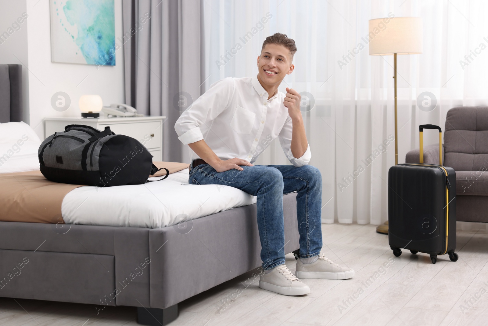 Photo of Smiling guest relaxing on bed in stylish hotel room