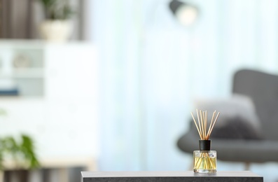 Photo of Aromatic reed air freshener on table against blurred background