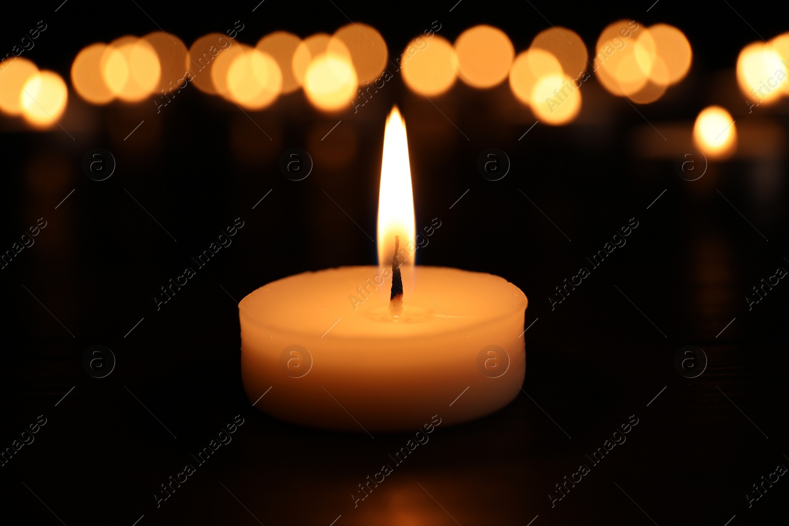 Photo of Burning candle on dark surface. Memory day