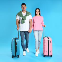Photo of Happy couple with suitcases for summer trip on blue background. Vacation travel