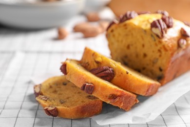 Photo of Delicious pumpkin bread with pecan nuts on tablecloth, closeup