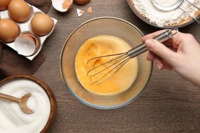 Photo of Woman whisking eggs at wooden table, top view
