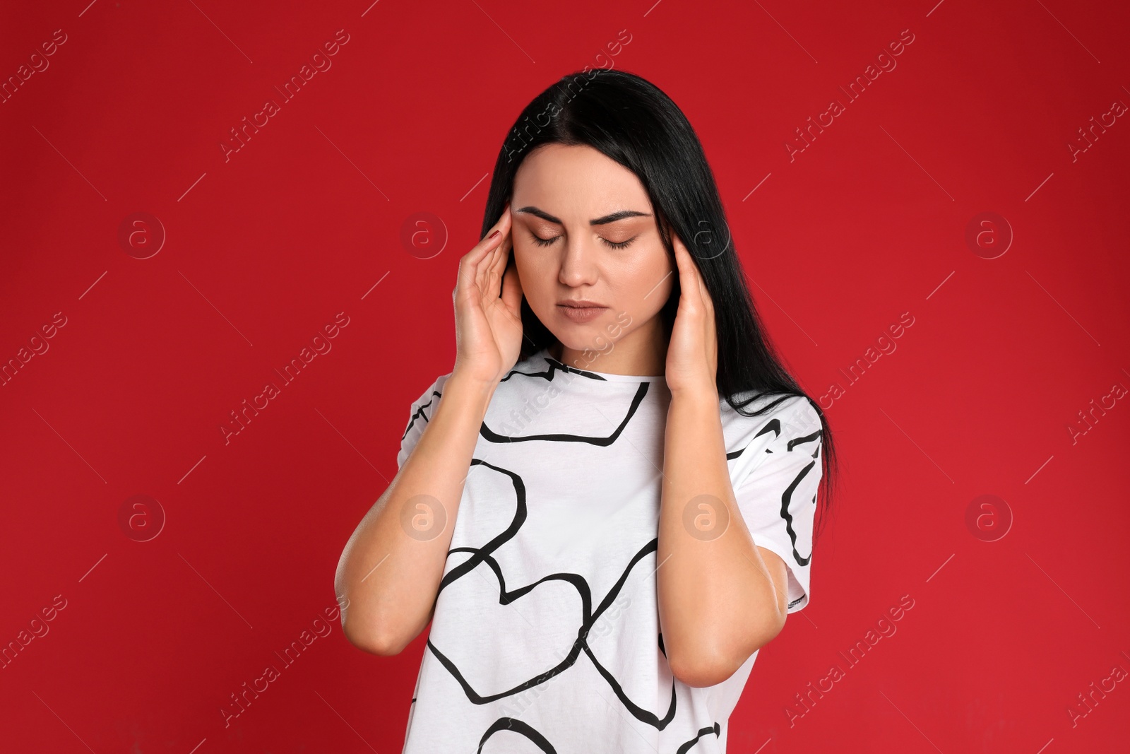 Photo of Young woman suffering from headache on red background