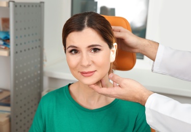 Professional otolaryngologist examining woman in clinic. Hearing disorder