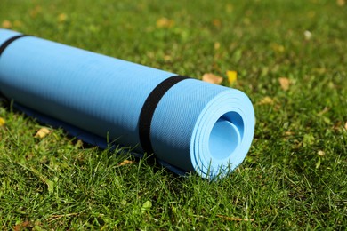 Photo of Blue karemat or fitness mat on fresh green grass outdoors, closeup