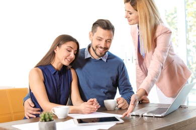 Female real estate agent working with couple in office