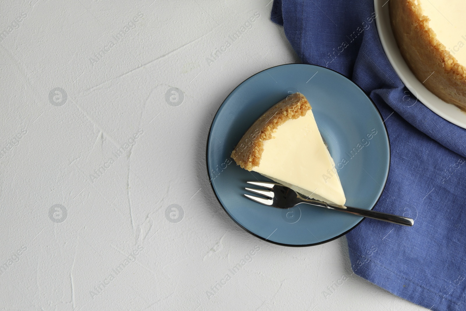 Photo of Piece of tasty vegan tofu cheesecake and fork on white table, flat lay. Space for text