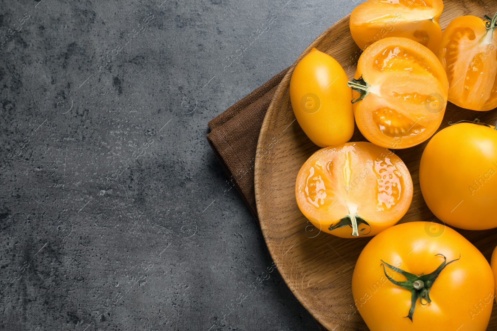 Photo of Fresh ripe yellow tomatoes on grey table, top view. Space for text