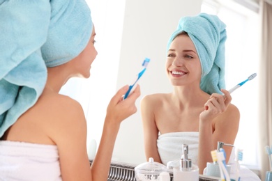 Photo of Young beautiful woman with toothbrush near mirror in bathroom. Personal hygiene