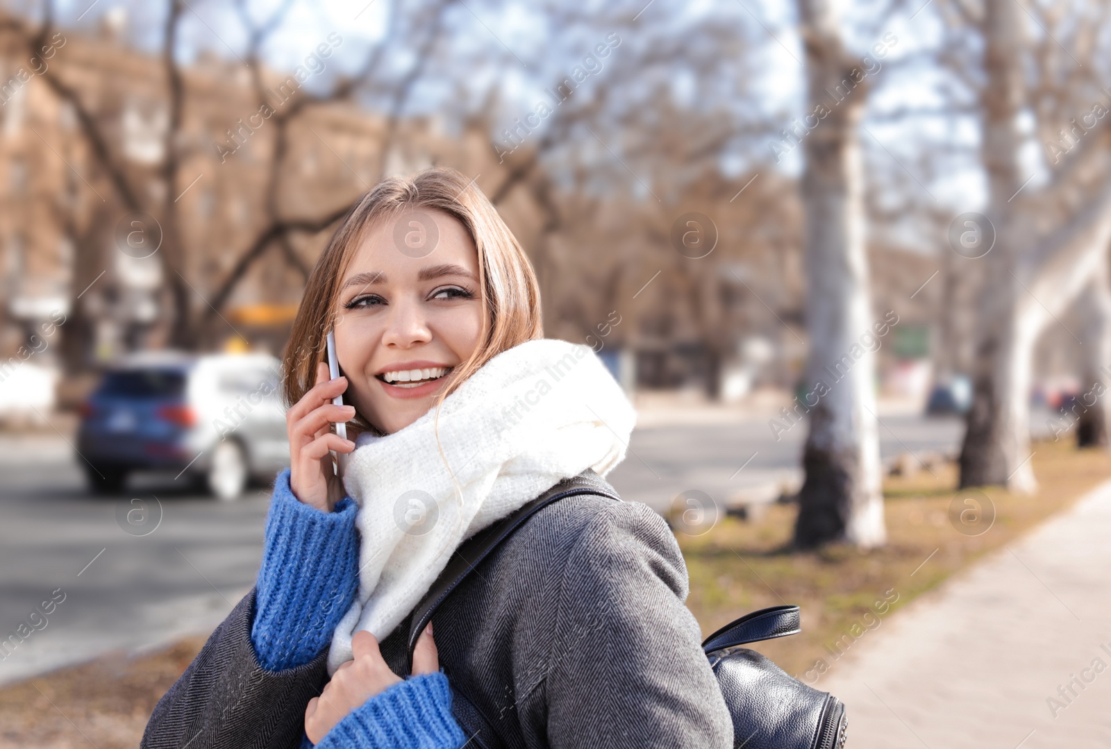 Photo of Portrait of happy young woman talking on phone outdoors