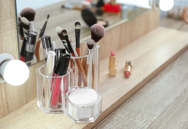 Organizer with cosmetic products for makeup on table near mirror