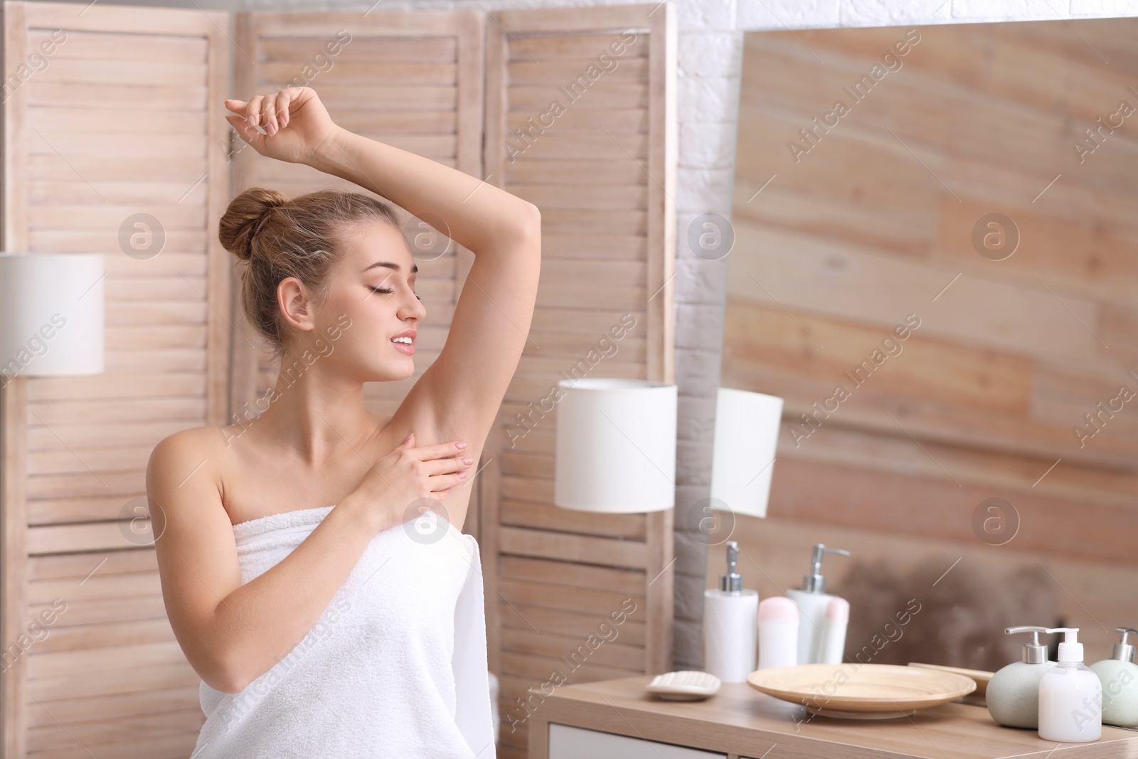 Photo of Beautiful young woman after shower in bathroom. Concept of using deodorant