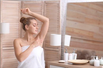 Photo of Beautiful young woman after shower in bathroom. Concept of using deodorant