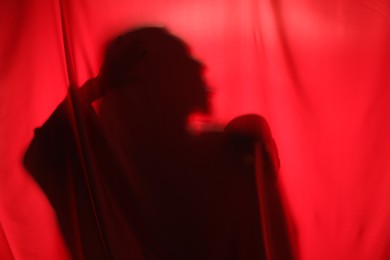 Silhouette of creepy ghost with skull behind red cloth, space for text