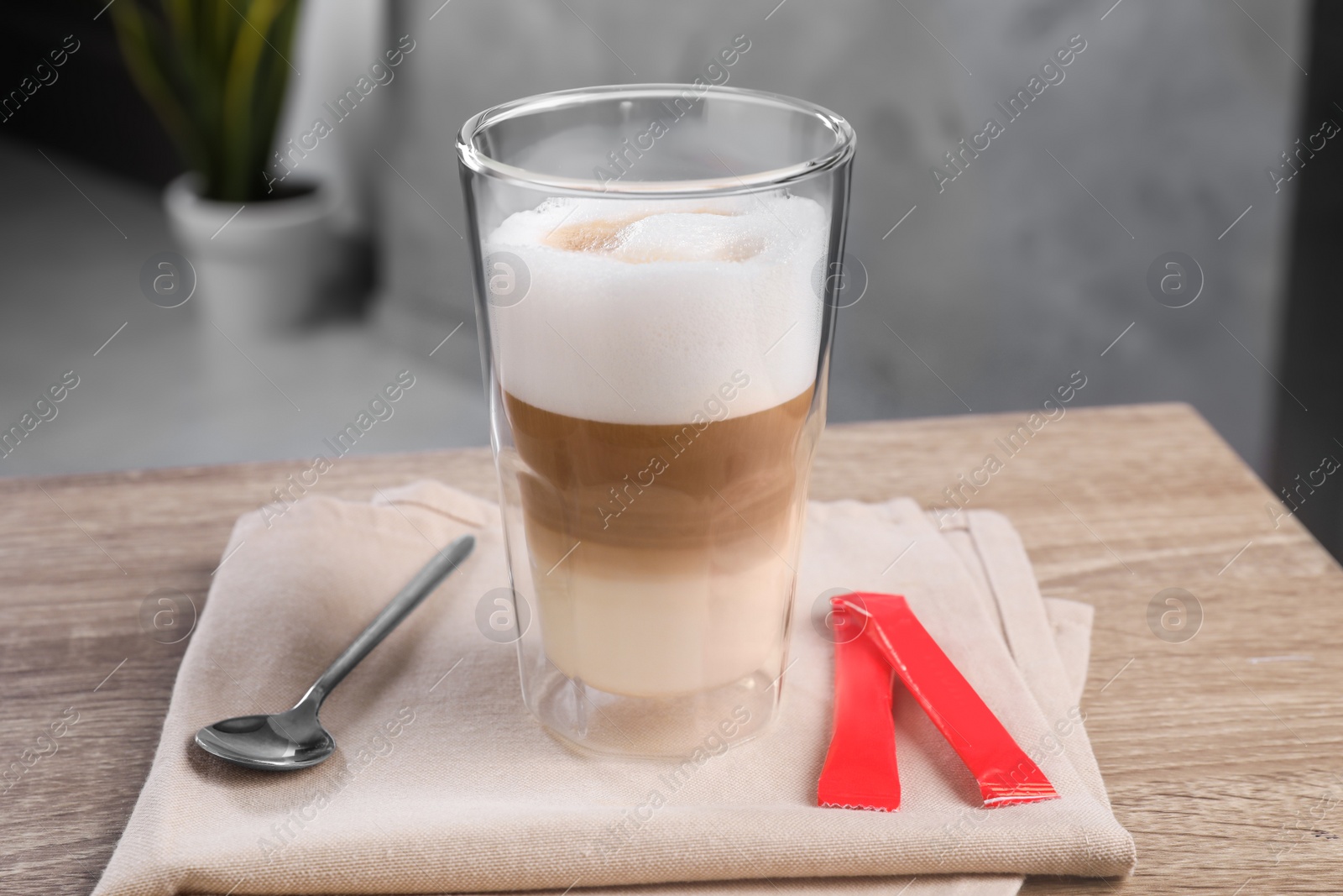 Photo of Delicious coffee in glass and sugar packets on wooden table