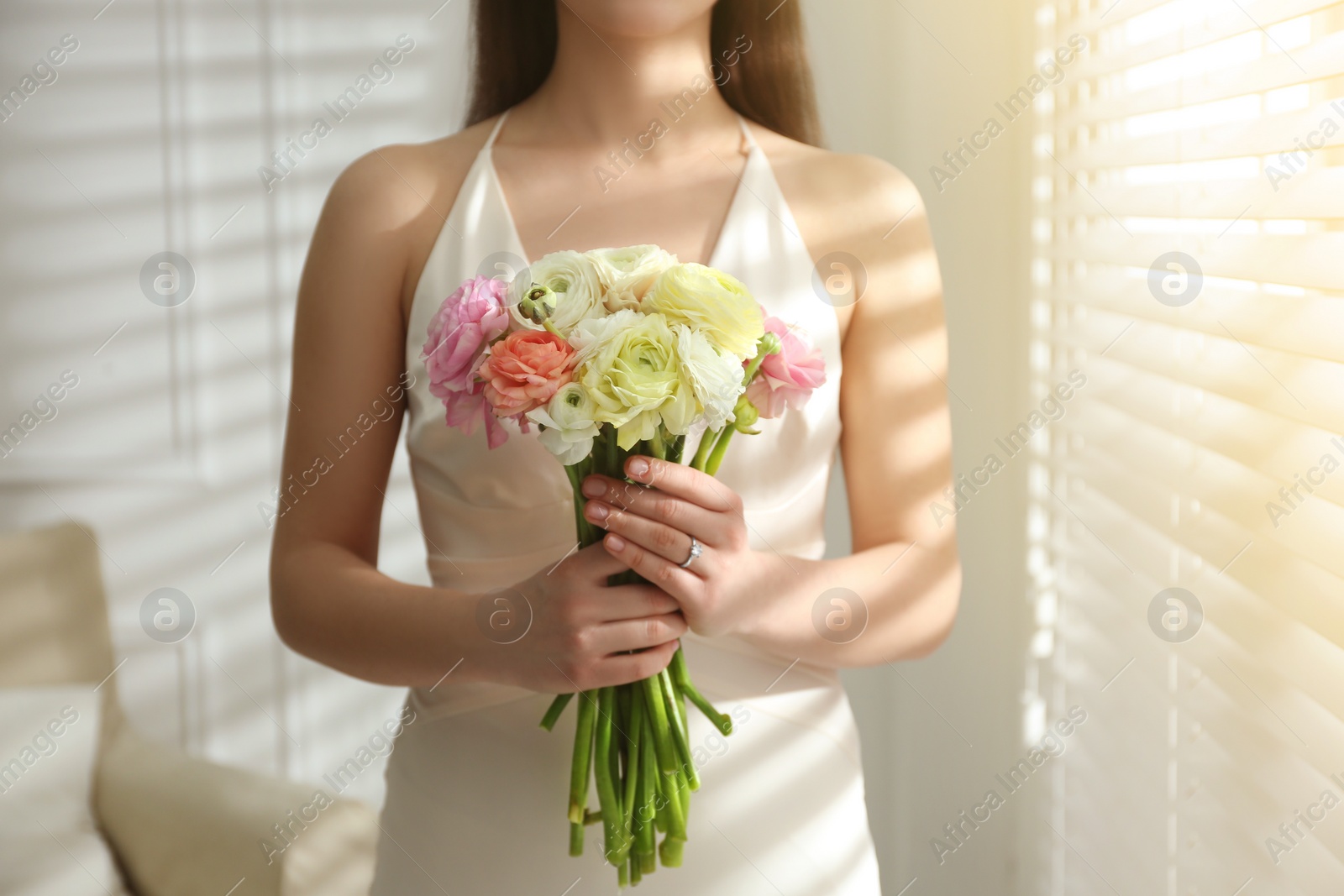 Photo of Bride with beautiful ranunculus bouquet indoors, closeup