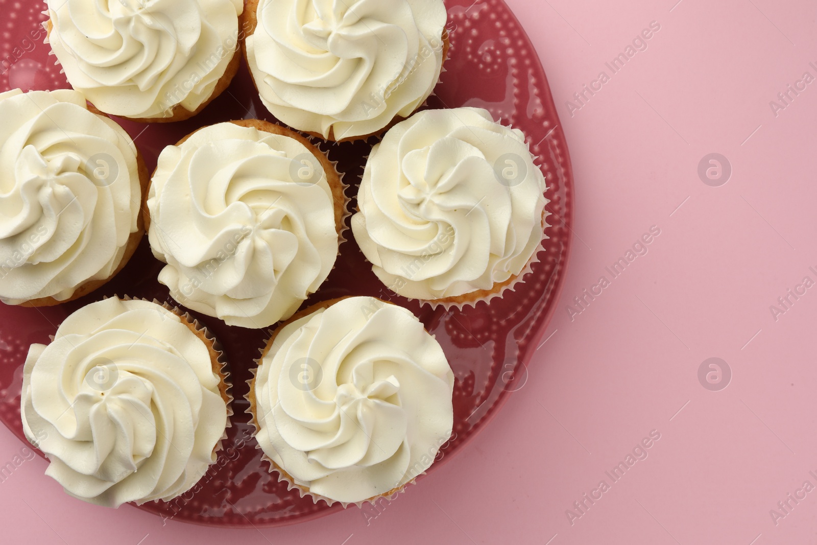 Photo of Tasty vanilla cupcakes with cream on pink background, top view. Space for text