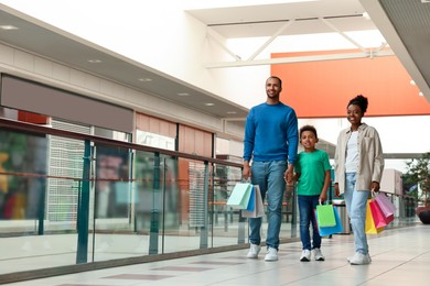 Family shopping. Happy parents and son with colorful bags in mall