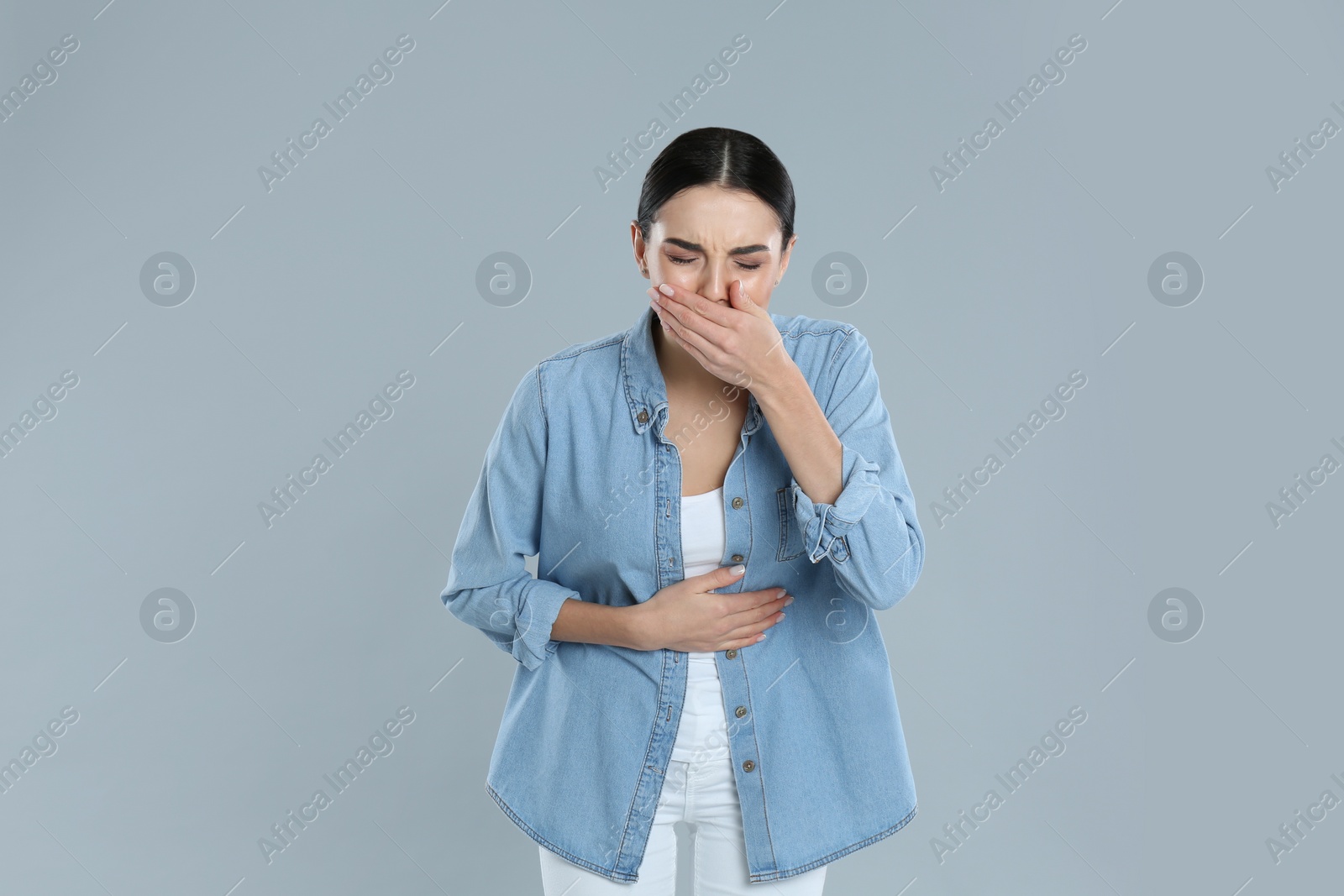 Photo of Woman suffering from stomach ache and nausea on grey background. Food poisoning