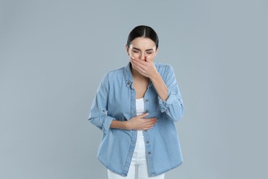Photo of Woman suffering from stomach ache and nausea on grey background. Food poisoning