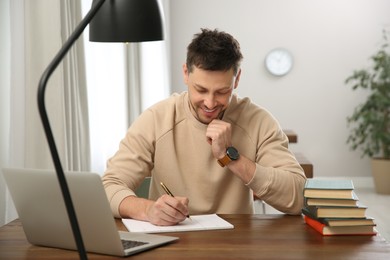 Man with laptop and books studying at table in library