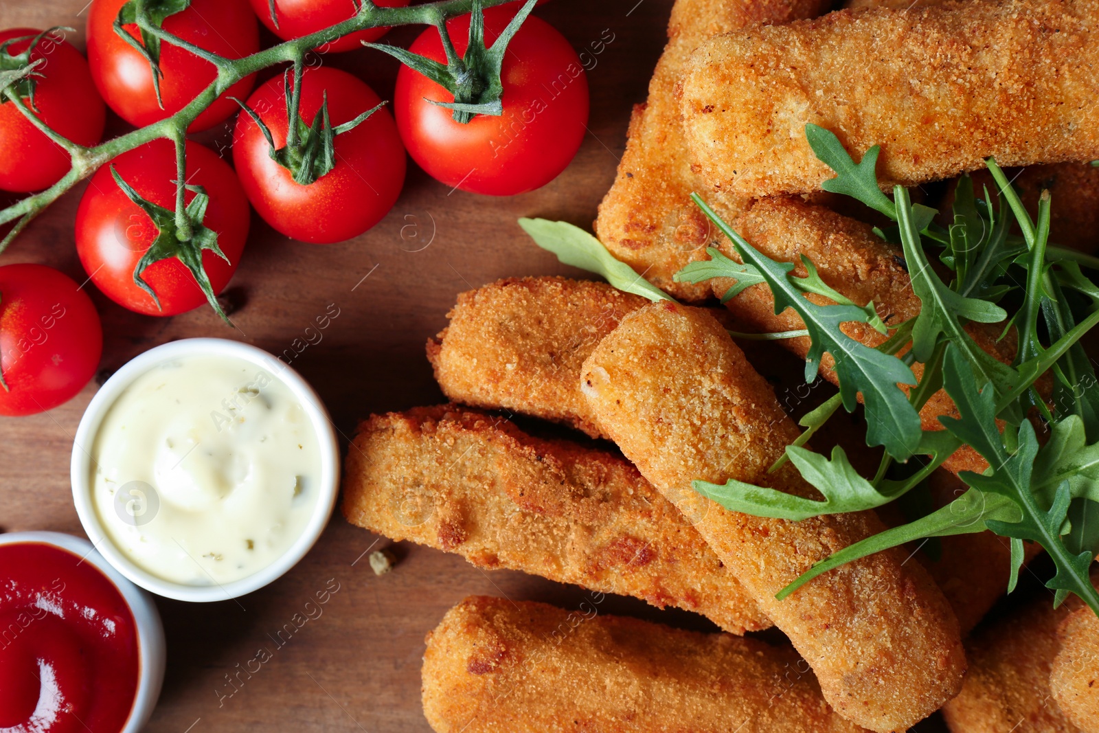 Photo of Cheese sticks with sauces and tomatoes on wooden background, closeup