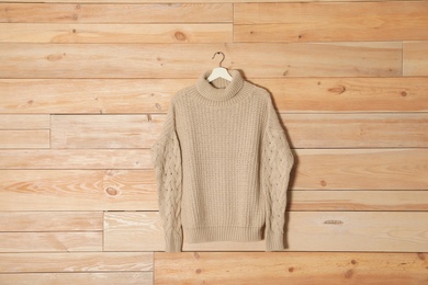 Photo of Hanger with stylish sweater on wooden background