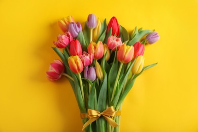 Photo of Bunch of beautiful tulips on yellow background, top view