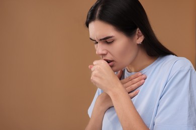 Photo of Woman coughing on brown background, space for text. Cold symptoms