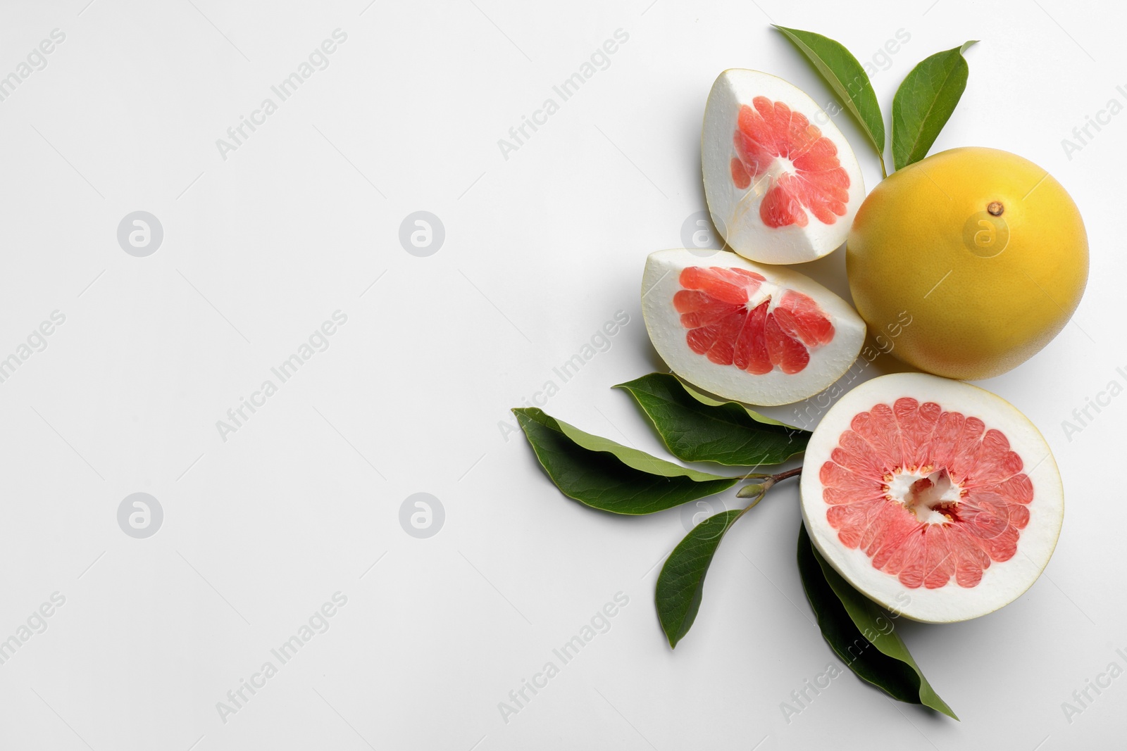 Photo of Fresh cut and whole pomelo fruits with leaves on white background, top view. Space for text