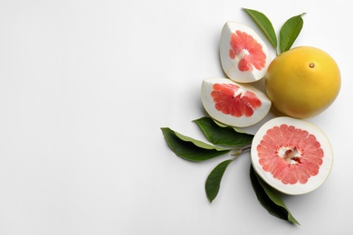 Photo of Fresh cut and whole pomelo fruits with leaves on white background, top view. Space for text