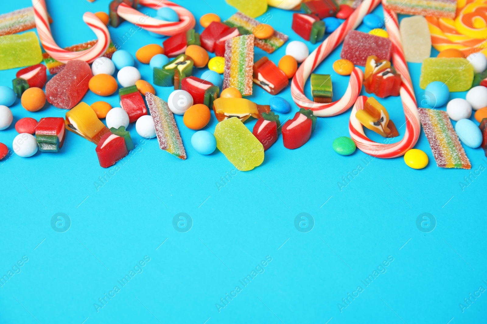 Photo of Different yummy candies and space for text on color background