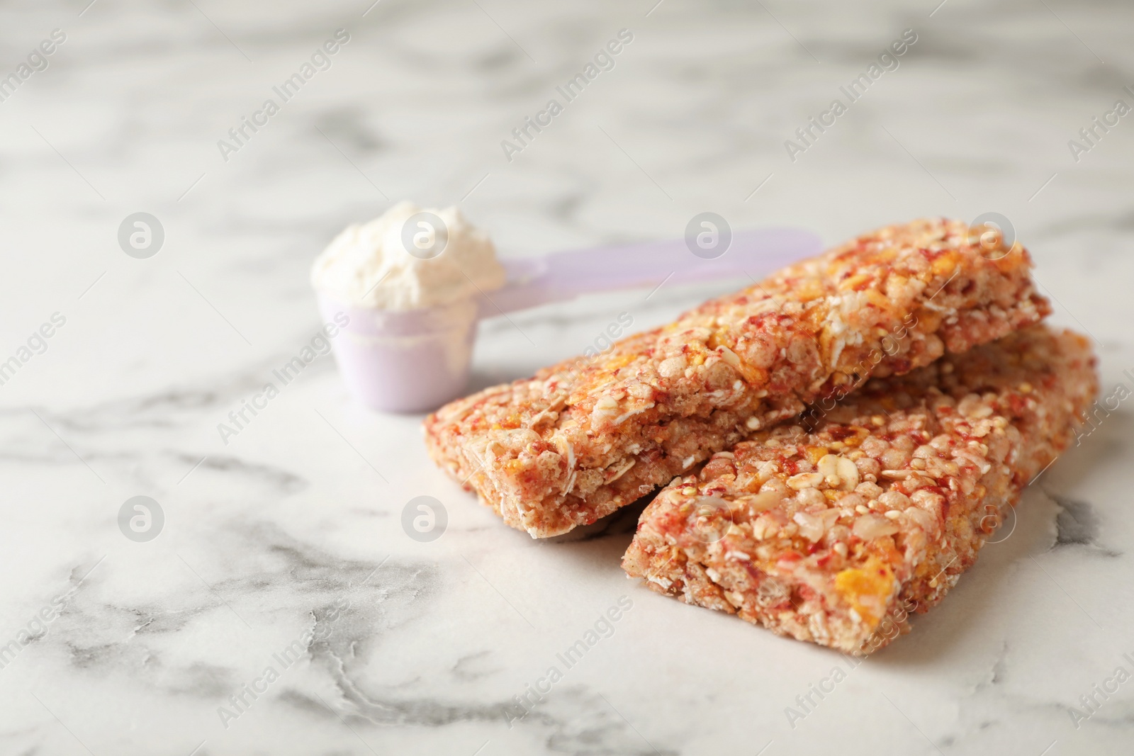 Photo of Tasty protein bars and scoop of powder on marble table