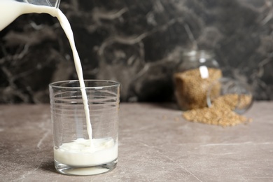 Photo of Pouring hemp milk into glass on table, closeup