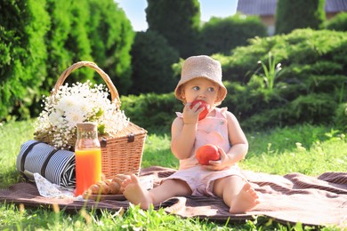 Photo of Cute little baby girl with nectarines on picnic blanket in garden