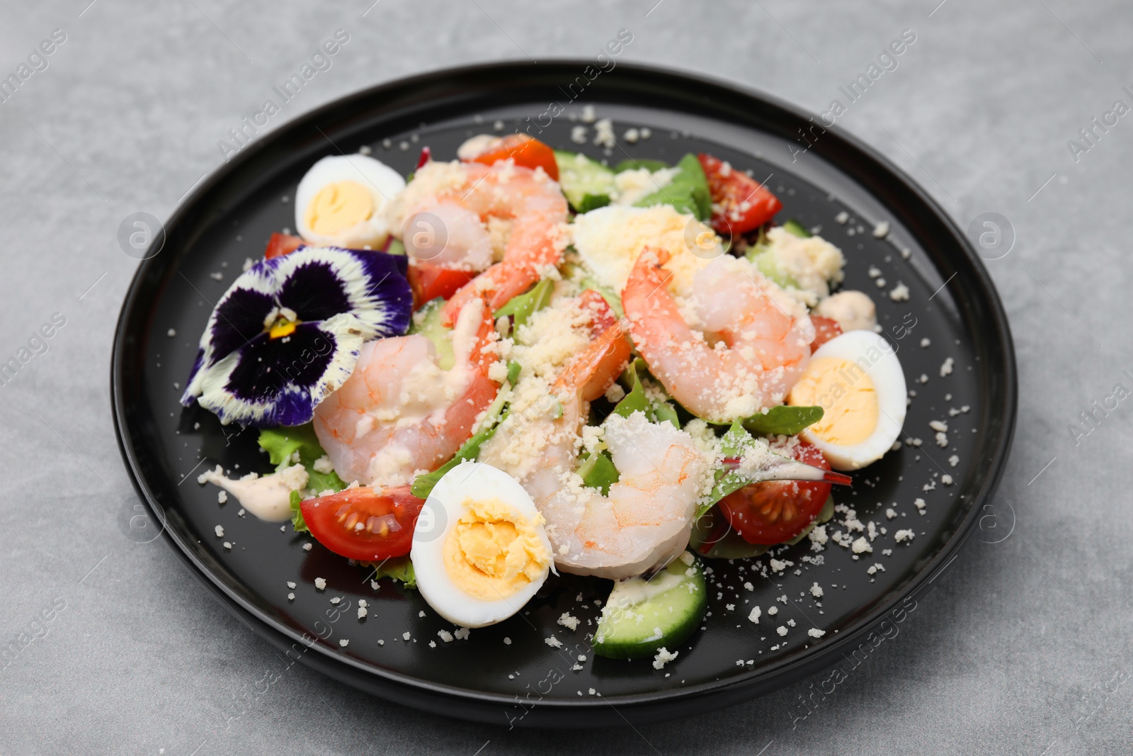 Photo of Delicious Caesar salad with shrimps on grey table, closeup