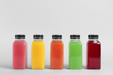 Bottles with delicious colorful juices on light background