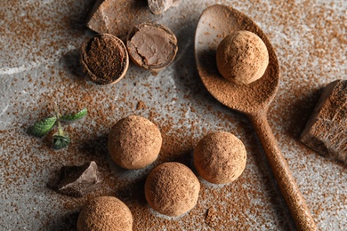 Flat lay composition with spoon and chocolate truffles on grey background