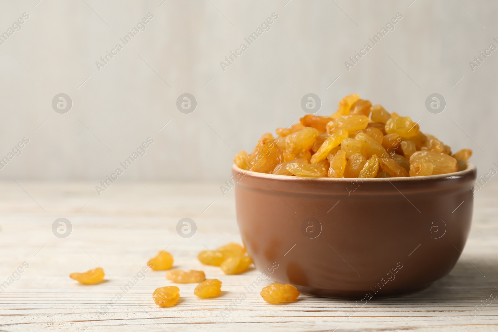 Photo of Bowl with raisins on wooden table, space for text. Dried fruit as healthy snack