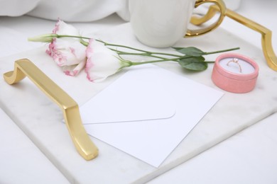 Photo of Tray with flowers and beautiful engagement ring in box on white bed, closeup