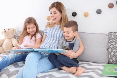 Nanny reading book to little children at home