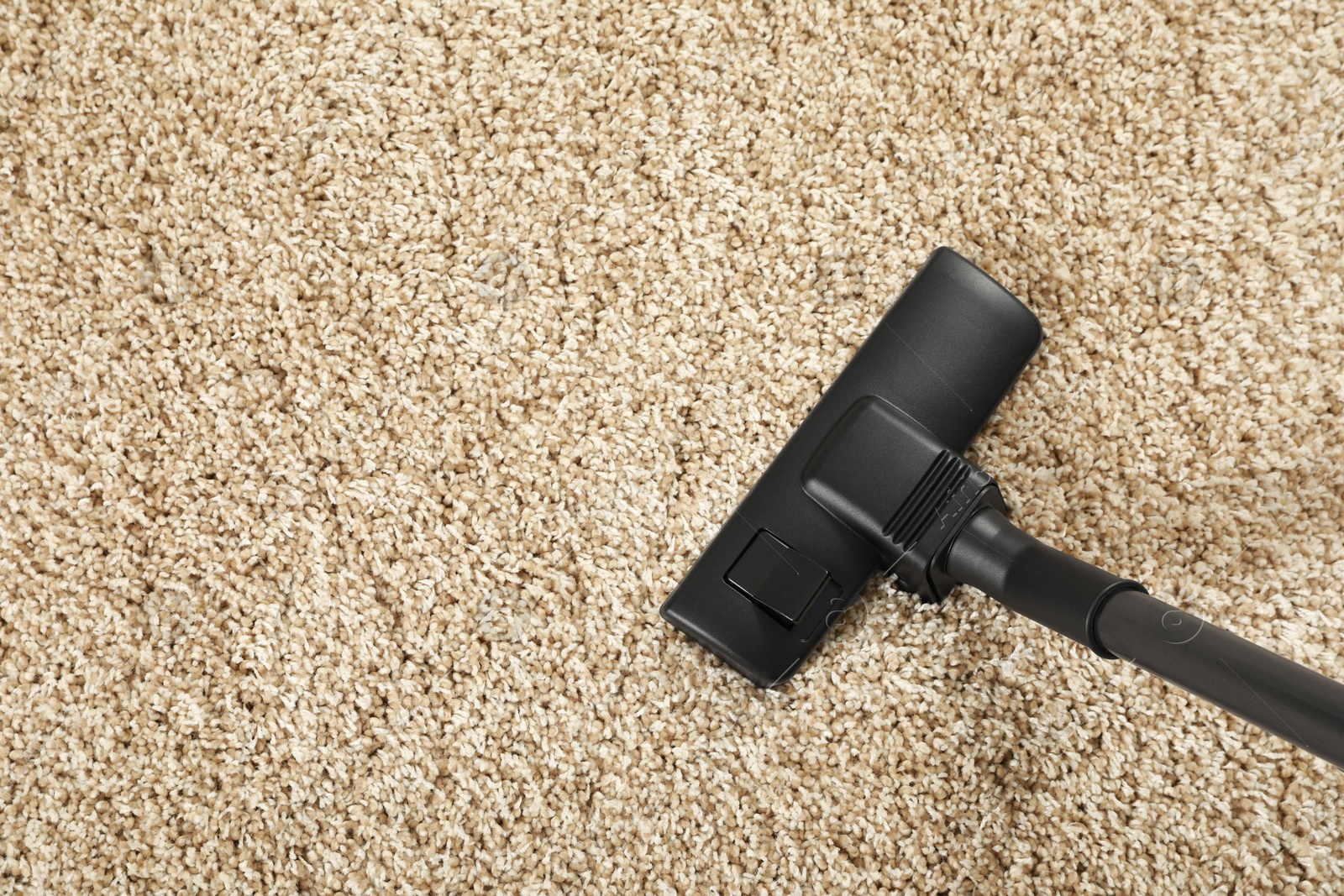 Photo of Removing dirt from beige carpet with modern vacuum cleaner, top view. Space for text