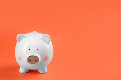 Photo of White piggy bank on orange background. Space for text