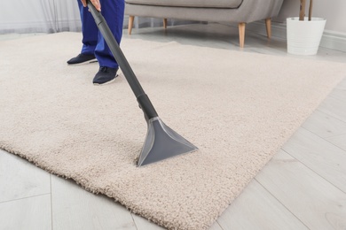 Photo of Man removing dirt from carpet with vacuum cleaner indoors, closeup. Space for text