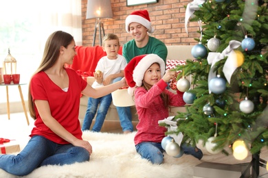 Happy parents and children decorating Christmas tree together at home
